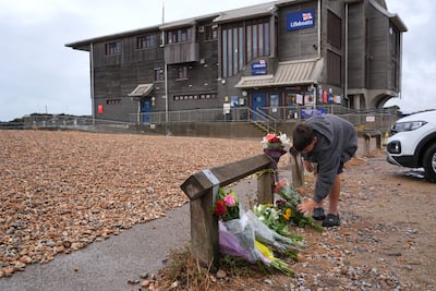 Child lays a floral tribute on the beach at Shoreham-by-Sea. PA