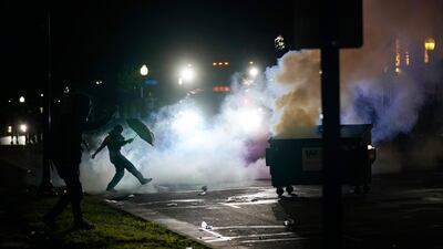 A protester kicks a smoke canister in Kenosha, Wisconsin. Outrage over the Sunday shooting of Jacob Blake, a Black man, by police spilled into the streets for a third night. AP Photo