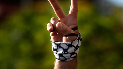 A protester flashes a victory sign with a representation of a Palestinian headscarf on his hand, during a protest in Beirut, Lebanon. AP Photo