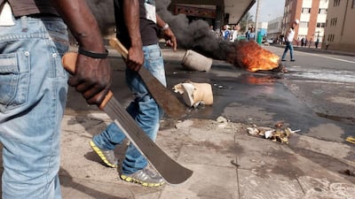 Men armed with machetes make their way to street clashes with police in Durban, South Africa. Tebogo Letsie / AP Photo