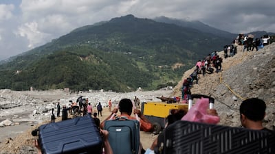 People carrying their belongings walk through Betrawati in Nuwakot district towards their village in Rasuwa, following deadly flash floods and a mudslide, in Nepal. Reuters