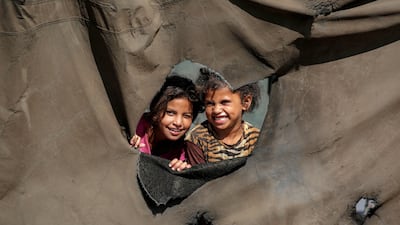 Children look on from a hole in a tent at a camp for displaced Palestinians in northern Nuseirat in central Gaza. AFP