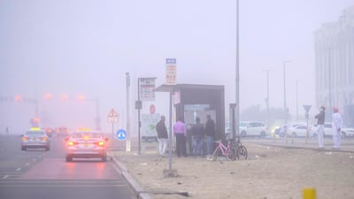 People wait at the bus stop on a foggy morning in Khalifa City, Abu Dhabi. Victor Besa / The National