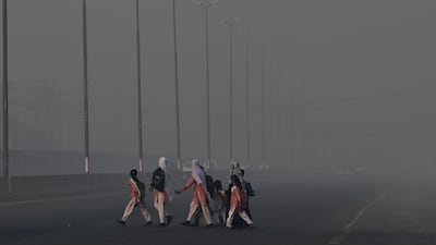 Visibility is poor as schoolchildren cross a road in dense smog in Lahore, Pakistan. AFP