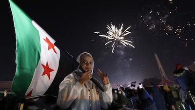 A young woman holds the Syrian flag on New Year's Eve near Umayyad Square in Damascus. AFP