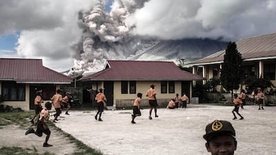 Indonesian school children play outside as mount Sinabung volcano spews thick volcanic ash as seen from Karo, North Sumatra province. AFP Photo / February 10, 2017.