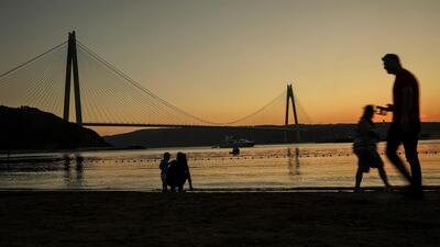 People walk on the seafront, on the Asian side of Istanbul, backdropped by the Yavuz Sultan Selim Bridge. AP