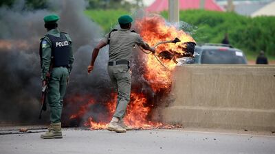 A police officer removes burning tires from the road, as protesters set up fires to block traffic along Airport Road in Abuja, Nigeria September 4, 2019. Reuters
