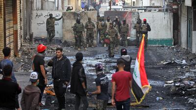 Members of the Iraqi security forces and anti-government protesters gather in front of a concrete barrier on al-Rasheed street in the capital Baghdad, during a lull in the anti-government protests. AFP