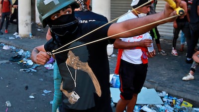 An anti-government protester throws a stone at security forces during clashes in the al-Rasheed street in Baghdad, Iraq. AP Photo