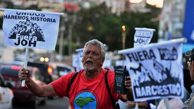 A supporter of the Libertad y Refundacion (LIBRE) opposition party holds signs reading "Together we will make history. JOH out" and "Out narco-country" as he demonstrates against Honduran President Juan Orlando Hernandez in Tegucigalpa. AFP