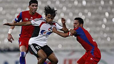 Ahmed Dada of Al Jazira, centre, struggles to break free from the shirt-pulling Ibrahim Saif of Al Shaab.