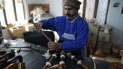 A Pakistani worker fixes a component to make a set of bagpipes at the factor. AFP.