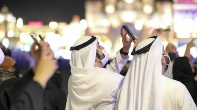 A man watches as Global Village attempts a Guinness World Record for the highest firework display. Twenty skydivers landed at the Dubai attraction with fireworks. Chris Whiteoak / The National