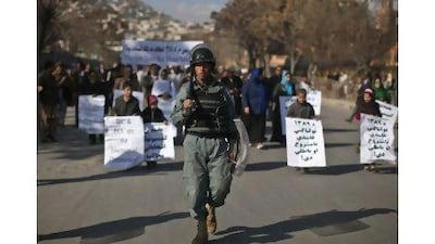 An anti-riot policeman walks ahead of marchers in a protest in Kabul yesterday by candidates in the September 18 Afghan parliamentary elections.