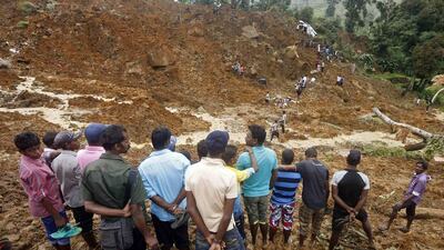 A group of men stand above the site of a landslide at the Koslanda tea plantation near Haldummulla on October 30, 2014. Hopes of finding survivors under the mud and rubble of the landslide are fading. Dinuka Liyanawatte/Reuters