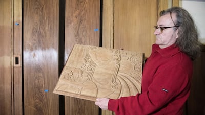 Conservator Thierry Palanque holds one of the low-relief carvings by the sculptor Louis Rigal that adorn the panelled interior. Christophe Morin for The National