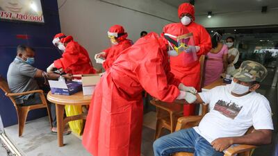 Sri Lankan health workers wearing protective equipment perform COVID-19 blood tests in Colombo. EPA