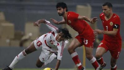Ahmed Dada, left, stumbles as Mamoud Abdulrahman and Sayed Jamal chase him during UAE's match against Bahrain at the Mohammed bin Zayed Stadium.