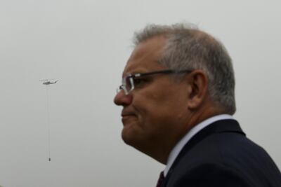 A fire fighting helicopter flies in the sky behind Australian Prime Minister Scott Morrison during a visit to HMAS Albatross in Nowra, New South Wales, Australia, 5 January 2020. EPA
