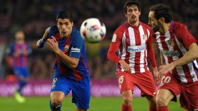 Luis Suarez eyes the ball as Atletico Madrid players look to defend. Lluis Gene / AFP