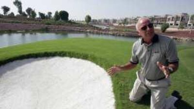 Bob Knott kneels down by one of the 102 bunkers, full of fresh, white sand, which are dotted around the par-72 course designed by Greg Norman.