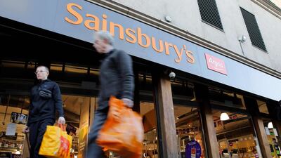 Shoppers walk past a Sainsbury's and Argos sign above the entrance to a Sainsbury's supermarket store in London. Sainsbury has announced 3,500 job cuts on November 5, mainly from the Argos chain it bought in 2016. AFP