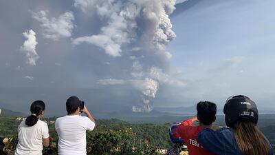 People take photos of a phreatic explosion from the Taal volcano as seen from the town of Tagaytay southwest of Manila. AFP