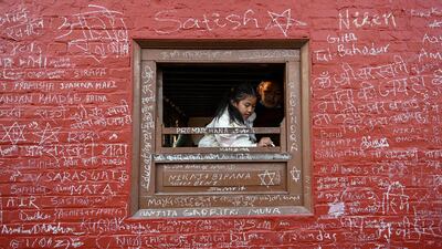 A child writes a message on a window frame at a temple during the Hindu festival of Basanta Panchami in Kathmandu, Nepal. AFP