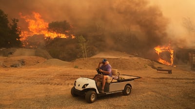 A resident drives a golf cart as he leaves his property while the so-called Canyon Fire burns in Halsey Canyon, California. AP