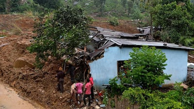 Sri Lankan residents stand outside a damaged building at the site of a landslide caused by heavy monsoon rains in Koslanda village in central Sri Lanka on October 29, 2014.Ishara S. Kodikara/ AFP Photo