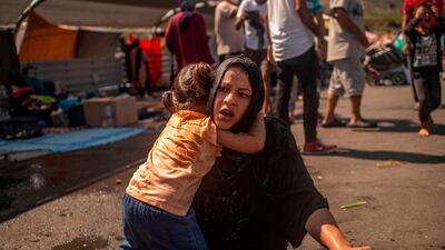 A migrant woman and a girl react, having been cleaned with water after police threw teargas. AFP