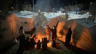 Earthquake survivors spend the night as they sit around a fire near a makeshift tent in a park in Sivrice, Turkey. Getty Images
