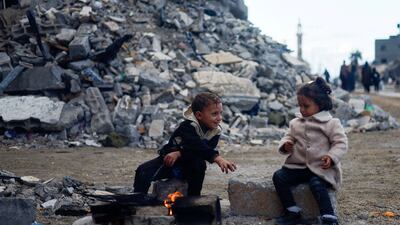 Palestinian children sit by the fire next to the rubble of a house hit in an Israeli strike in Khan Younis, southern Gaza Strip. Reuters