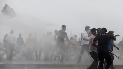 Supporters of the ruling party run as riot police fire tear gas during clashes in Colombo, amid the country's economic crisis. Reuters