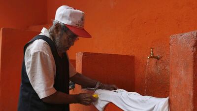 A man uses a public tap to wash his clothes in the Rocinha Favela. Barbara Walton / EPA