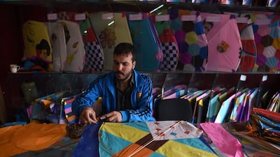 A kite vendor cuts tissue paper as he makes a kite in a shop in Shor Bazaar in Kabul.