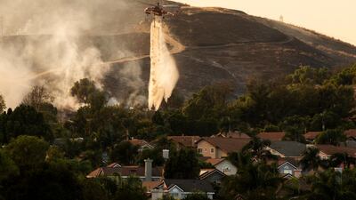 A helicopter makes water drops over the Blue Edge Fire as firefighters work at controlling its spread by lighting back fires near homes in Butterfield Ranch, Orange County, South of Los Angeles, California. EPA