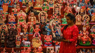 A woman picks up an idol used as a decoration ahead of Navratri in Chennai. AFP