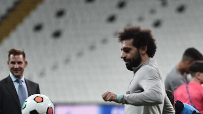 Liverpool's Egyptian midfielder Mohamed Salah plays football with a child at the end of a training session. AFP