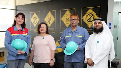 From left, Elizabeth Bredell, Tersia Corbitt, Mohammad Zahiruddin and Omer Jeelani at Emirates Global Aluminium in Dubai. Trained mental health first aiders wear aqua helmets. Pawan Singh / The National
