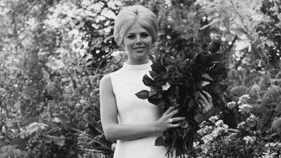 Portrait of actress Britt Ekland, wearing a white mini dress and knee socks, holding a bouquet of Red Planet 'Rose of the Year', at the Chelsea Flower Show, London, May 18th 1970. (Photo by Leonard Burt/Central Press/Getty Images)