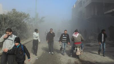 Civilians cover their noses as they walk near a site hit by what activists say are barrel bombs dropped by government forces at Maaret Al Naaman in Idlib. Abdalghne Karoof / Reuters
