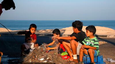 Palestinian children help fishermen to take out crabs from a fishing net on the shore of the Mediterranean Sea in Gaza City. AFP