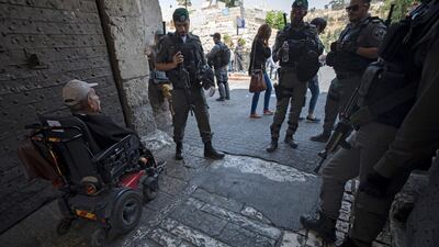 An elderly Palestinian man in a wheelchair passes Israeli security guards outside the Lions' Gate entrance of Jerusalem's Old City on July 23, 2017. Atef Safadi / EPA