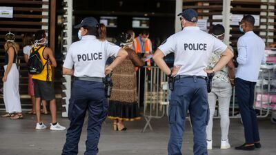 Police offciers stand guard as travellers wearing protective face masks queue for check-in on an Air Austral flight to Paris, from Dzaoudzi Airport in Petite Terre on the French Indian Ocean island of Mayotte, as measures to curb the spread of the COVID-19 (novel coronavirus) are maintained on Mayotte over concerns about the continued spread of the virus there and a fragile health system. AFP