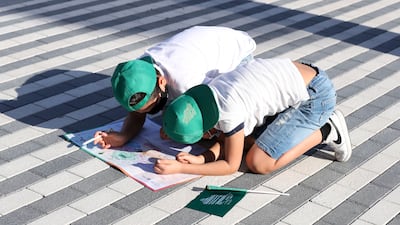 Children ing green caps – the colour of the Saudi flag – colouring in the Expo map.
