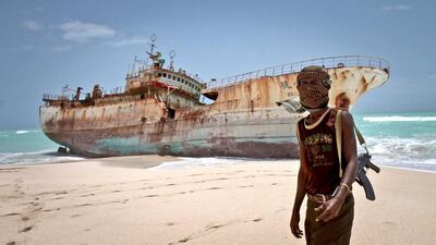 A masked Somalian pirate stands near a Taiwanese fishing vessel that washed ashore in Hobyo in 2012. A Dubai maritime security conference has heard the latest challenges facing seafarers in the region. Farah Abdi Warsameh / AP Photo