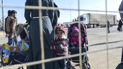 Syrian migrants and refugees wait in front of the Turkish Oncupinar crossing gate, near the town of Kilis,to return to Syria on February 9, 2016. Bulent Kilic / AFP Photo