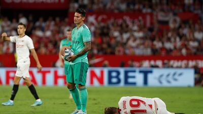 Real Madrid's James Rodriguez, centre, holds the ball as Sevilla's Luuk de Jong lays on the ground. AP Photo